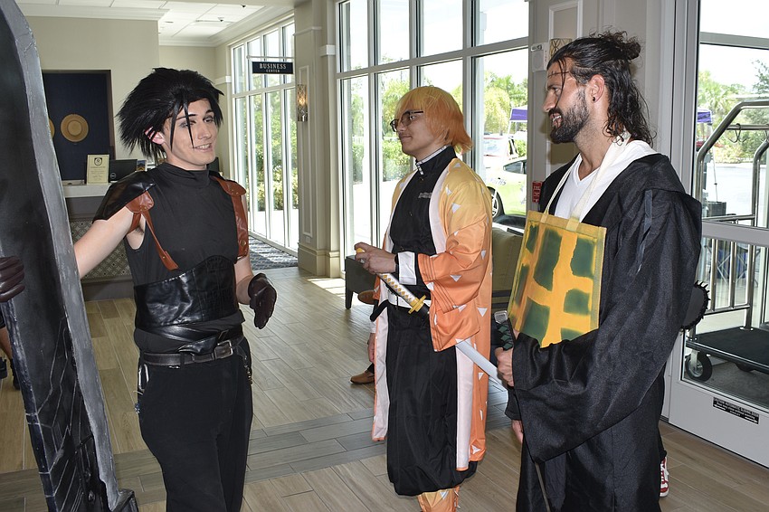 Keegan Strype, dressed as Zack Fair from Final Fantasy VII, Brian Andruskiewicz, dressed as Zenitsu Agatsuma from the Demon Slayer manga series, and Joe Foarile, dressed as Seguru Geto from the manga series Jujutsu Kaisen 0, talk with one another.