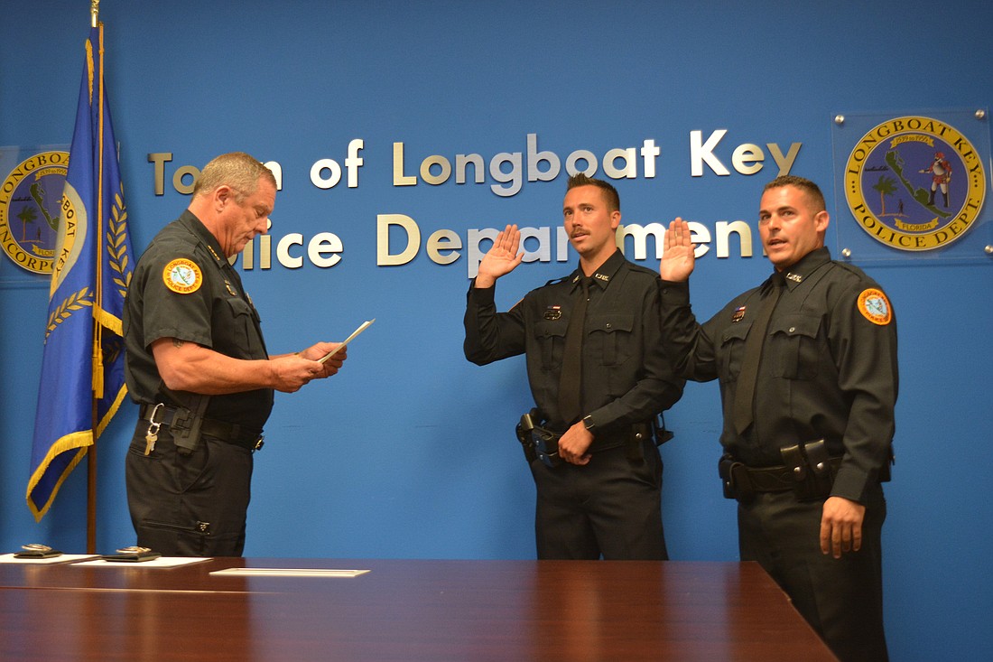 New Longboat Key Police officers Adam Swinford and Mike Rizzo recite the oath led by Chief of Police George Turner.