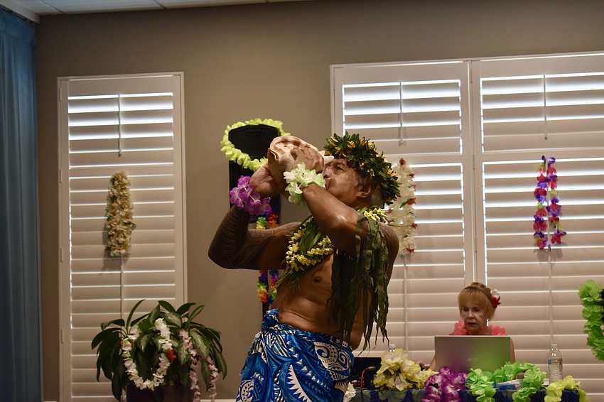 Pesi Mauga blows into a conch shell to start the luau.
