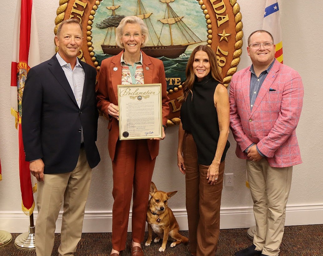 Mayor Jane Castor (second from left) and her dog, Desa, present a city of Tampa proclamation designating Aug. 19, 2023, as "Schifino Lee Day" to Schifino Lee partners Ben Lee (left), Paola Schifino and Jeff Philbin.
