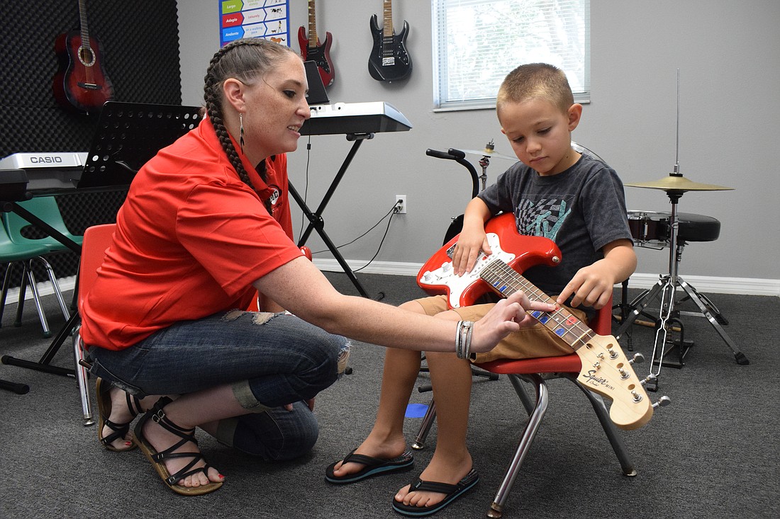 Music Compound music instructor Alicia Schiavone offers Palmetto 6-year-old Bennett Blumer a beginner's lesson guitar. "He has some type of performer in him, we just don't know how to channel it yet," says Hilary Blumer, Bennett's mother.