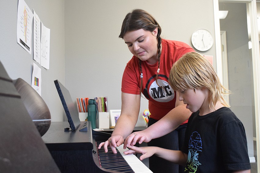 Music Compound music instructor Caitlyn Healey teaches Palmetto 6-year-old Jason Kirk how to play a C chord on the piano.