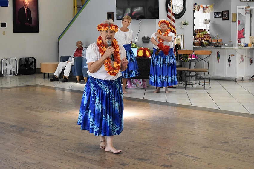 Barbara Winsten of Aloha Nui Hula Dancers offers the audience an introduction to a dance, standing alongside fellow members Irene Hagnan, and Ria Prowling.