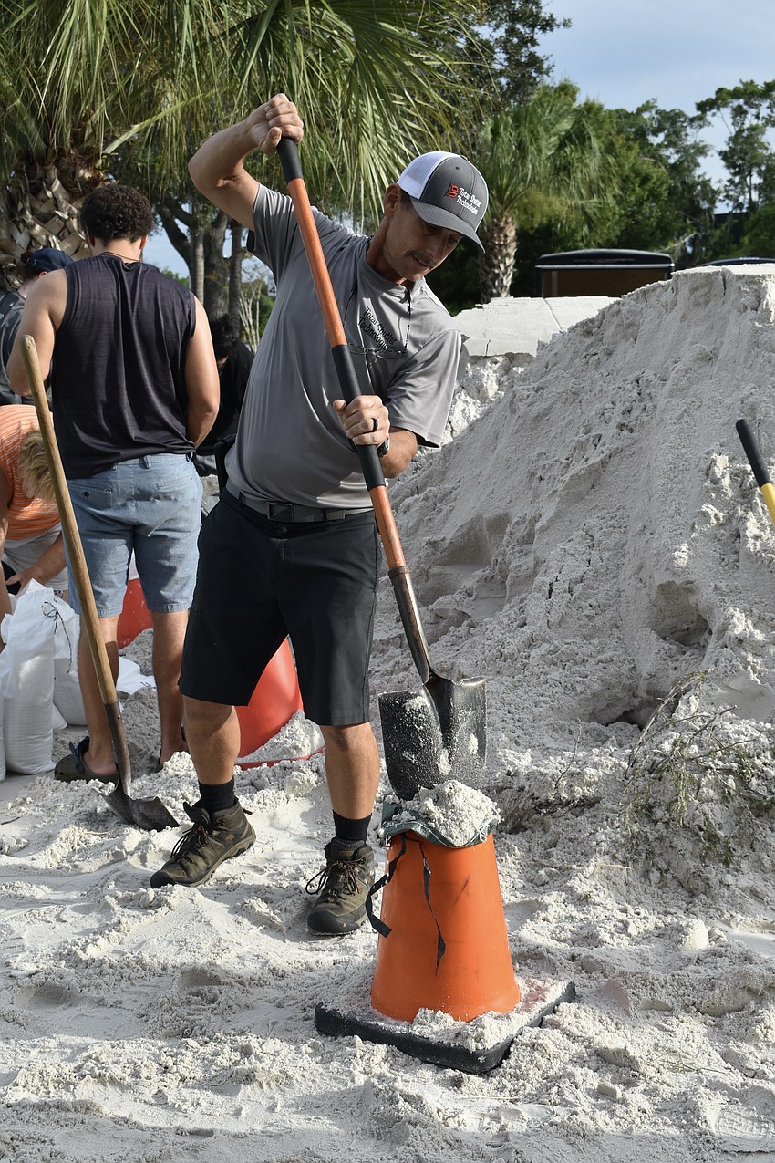 Ken Putz uses a cone to fill a sandbag at Ed Smith Stadium on Monday.