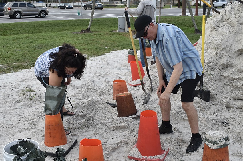 Alma and Glenn Johnson work together to fill sandbags at Ed Smith Stadium on Monday.