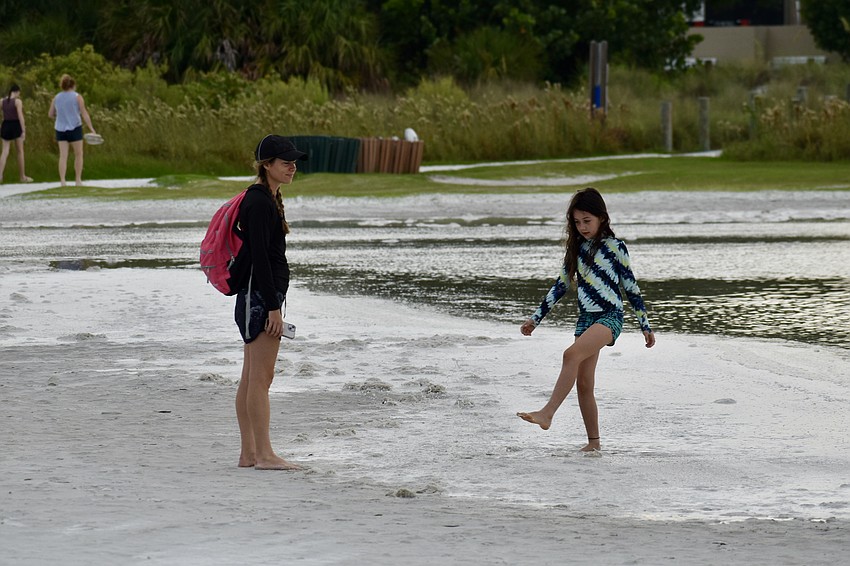 Kristin Johnson and 8-year-old Kylah Johnson explore the high tides resulting from the supermoon at Siesta Key Beach on Tuesday.