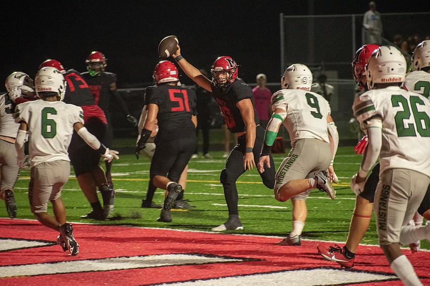 Cardinal Mooney senior quarterback Michael Valentino holds the ball aloft as he crosses the goal line for a touchdown.