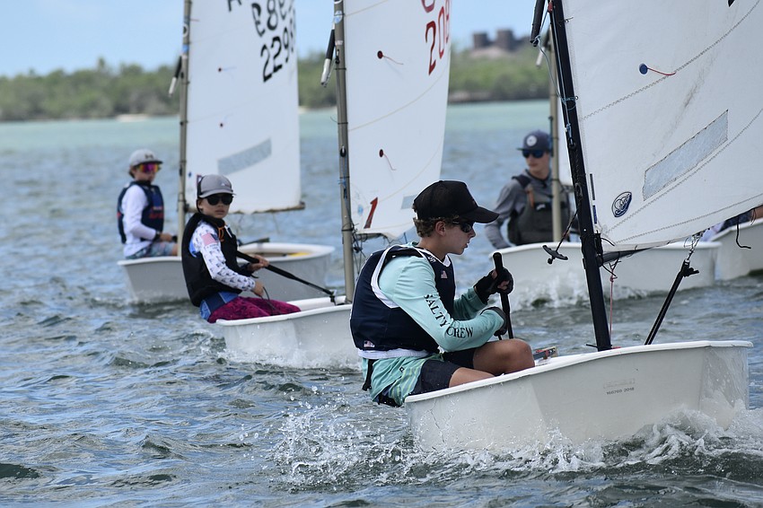 Tristan Lovell (Optimist RWB — Blue) of Davis Island Race Team, Piper Roberts (Optimist RWB — White) of Sarasota Yacht Club and Ryan Rossignol (Optimist RWB — Red of Sarasota Youth Sailing) emerge from a bend in the course.