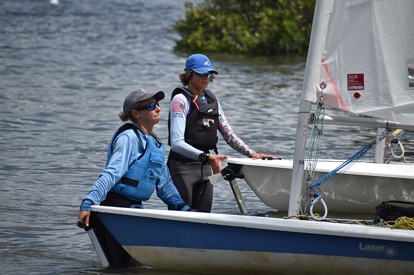 Sophia Woodbury of Sarasota Youth Sailing and Jackson Wilcox of Sarasota Sailing Squadron push their Lasers ashore after finishing the day's races.
