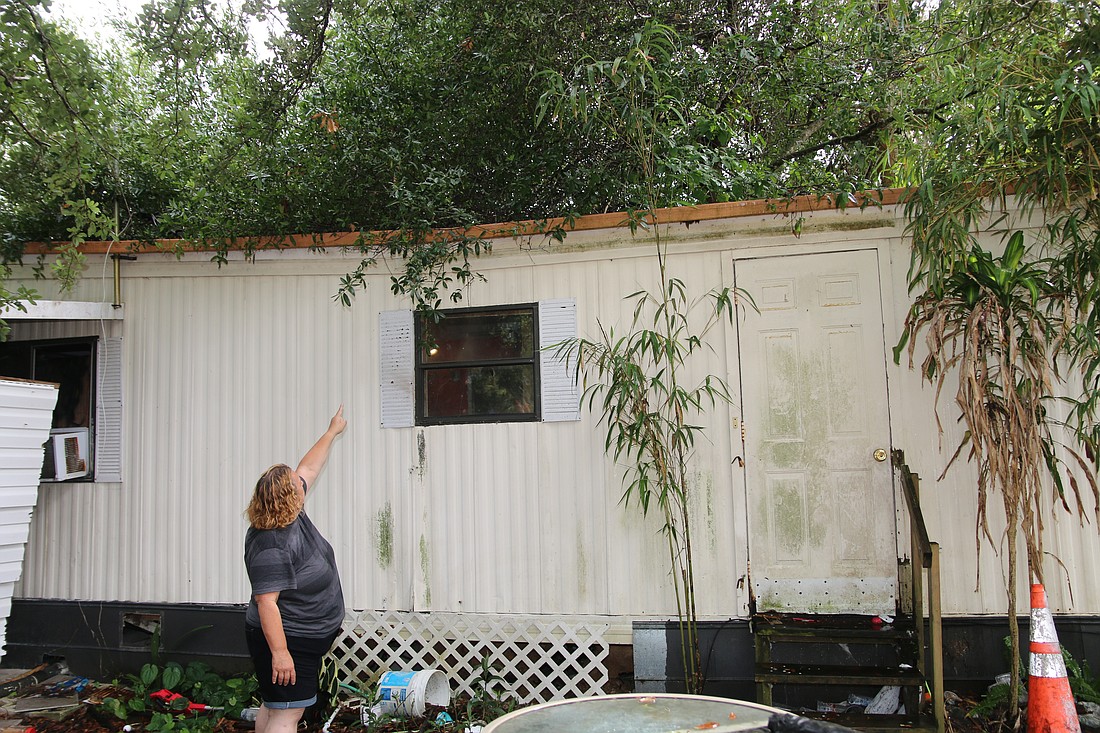 Jacqueline Dienst Rivers points to hurricane damage on the roof of her trailer. Photo by Jarleene Almenas