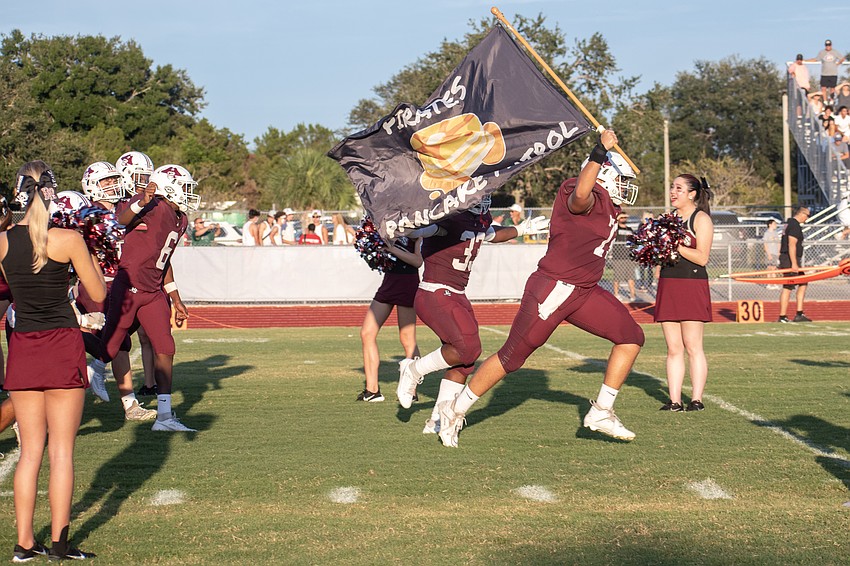 Braden River senior offensive tackle Brody Lind (72) leads the team onto the field carrying a 