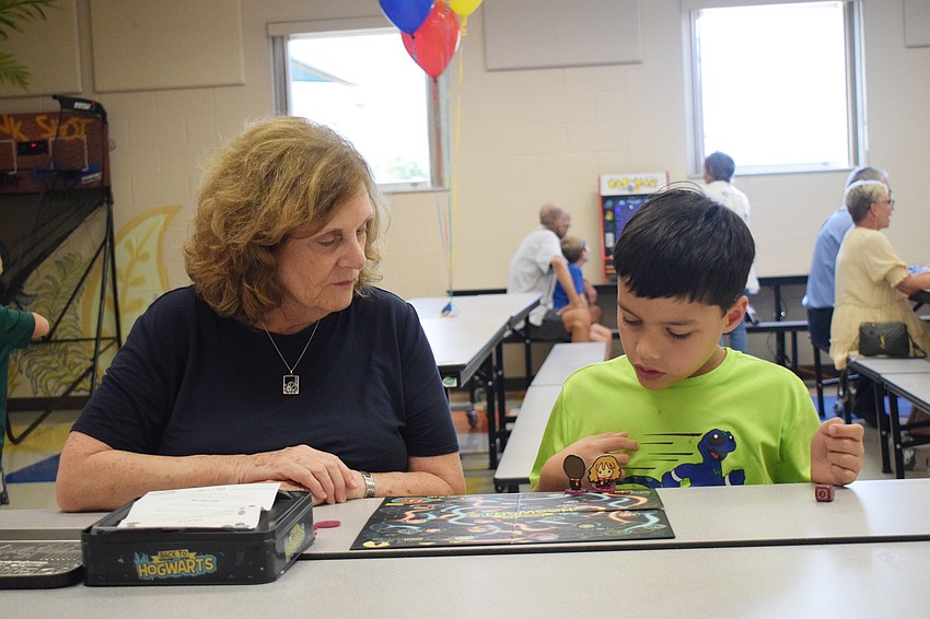 Jill Downie plays a board game with her grandson Paul Downie, a third grader. 