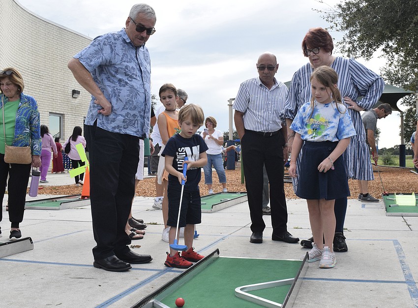 Tim O'Connor, kindergartner Shane Flynn, Anibal Colon, Brenda O'Connor and fourth grader Emmy Flynn enjoy a quick round of putt putt.