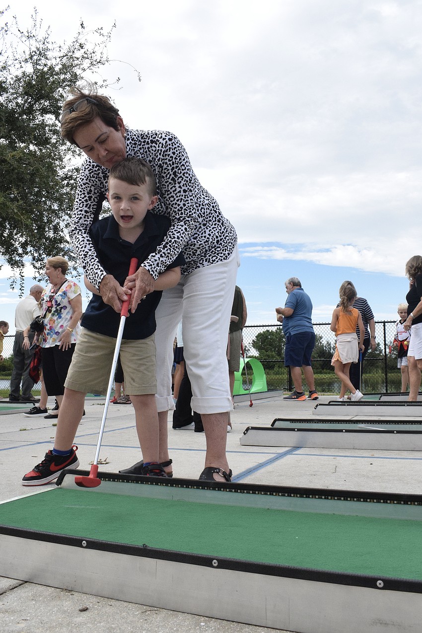 Julie McLaughlin teaches her grandson Mason Wisor, a first grader, how to putt. 