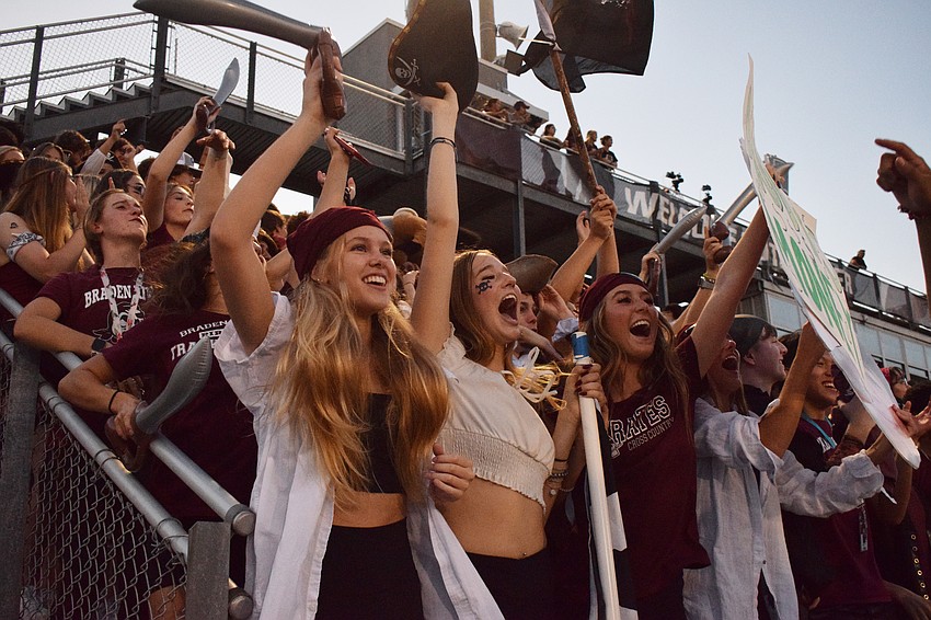 Braden River High School seniors Carly Taylor, Teagan Smit and Ella Brauch scream their hearts out to cheer on the football team.