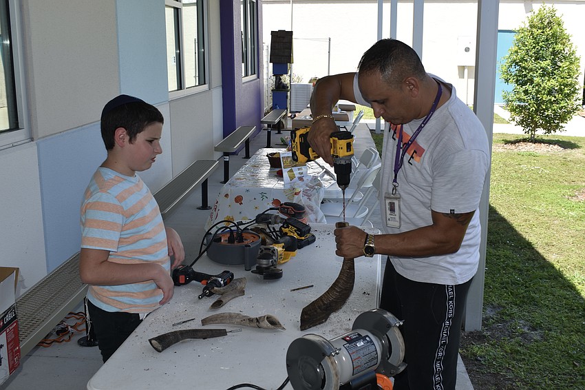 Ari Steinmetz, 11, watches facilities manager Jorge Ceballos drill a hole in one of the horns.