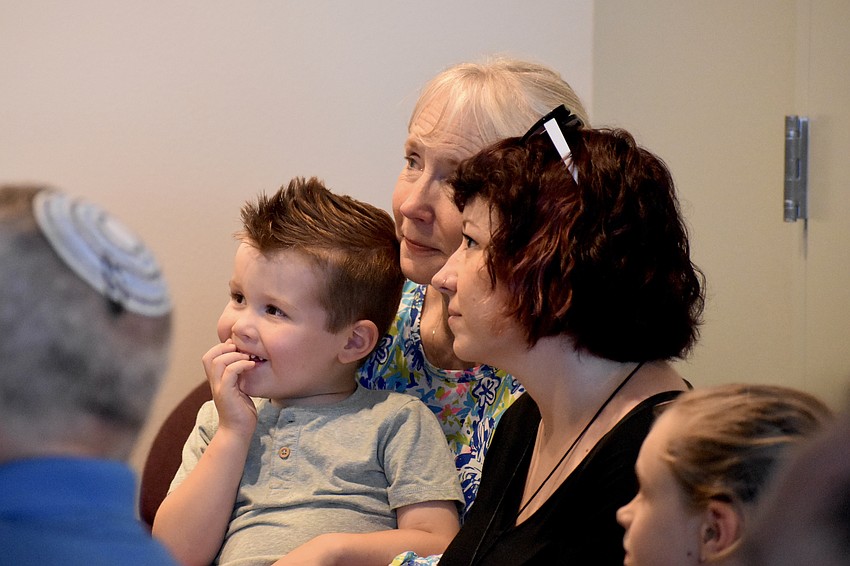 Beau Peterson, 4, reacts to Rabbi Chaim Steinmetz blowing the shofar as he sits with Debbie Valentin, and Sam Valentin