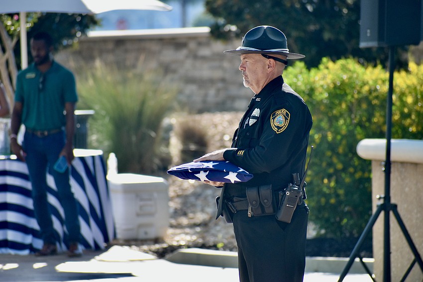 Officer Michael Clary prepares to present the flag to Plant City residnt Kelly Bjelke in memory of David Bjelke.