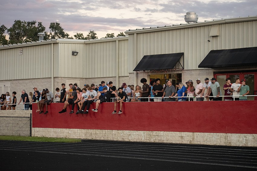 Fans watch the Cardinal Mooney-Riverview football game from the stadium wall.