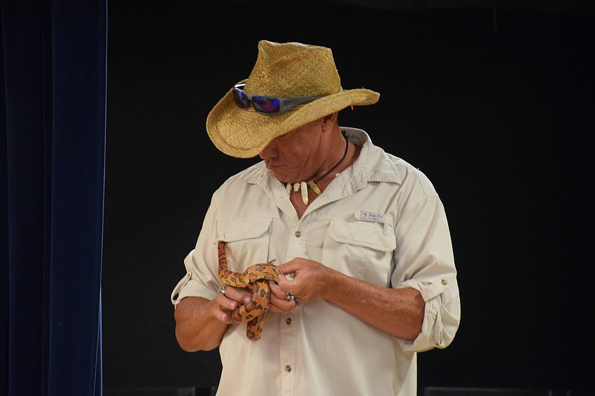 John Kenyon, an educational outreach programmer for Big Cat Habitat, watches as a red rat snack tries to sneak into his shirt pocket.