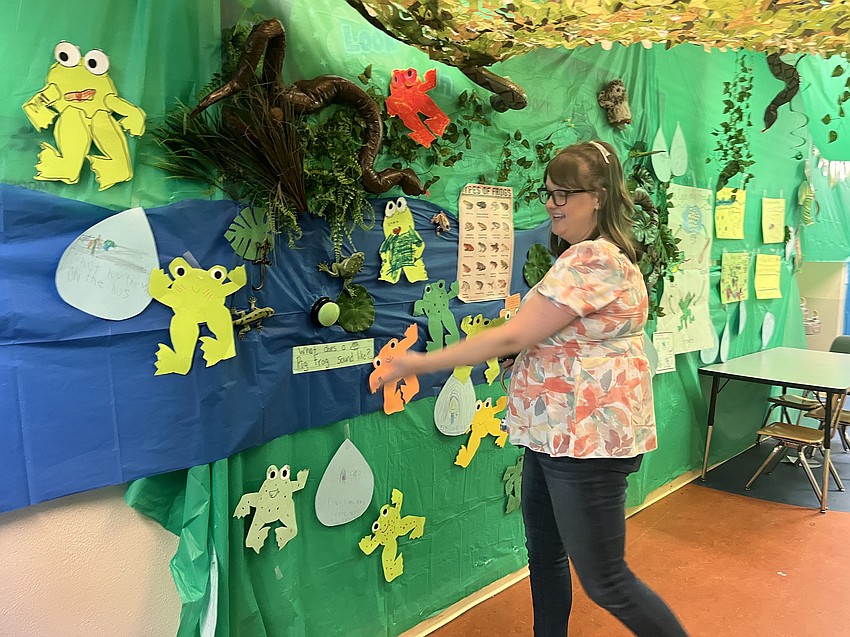 Courtney Walker, the media specialist, pushes a button that produces the sounds that a pig frog makes. Tammy Peters' first grade class spent the week learning about pig frogs and made their own frogs that were posted on the wall.