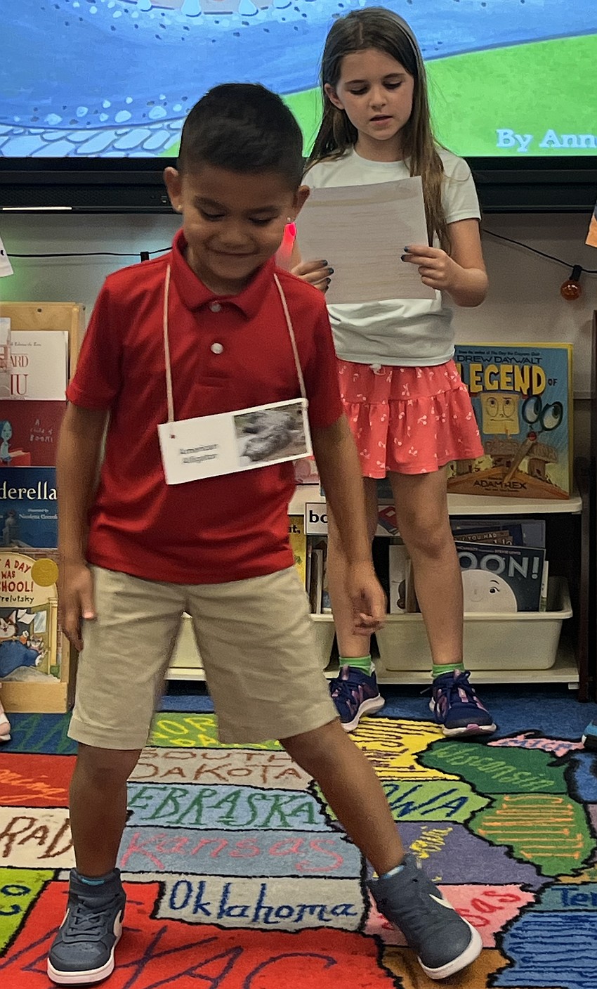 Second grader Braxxton Garcia-Pineda acts like he's digging a hole as Lillian Titus narrates. They are acting out 