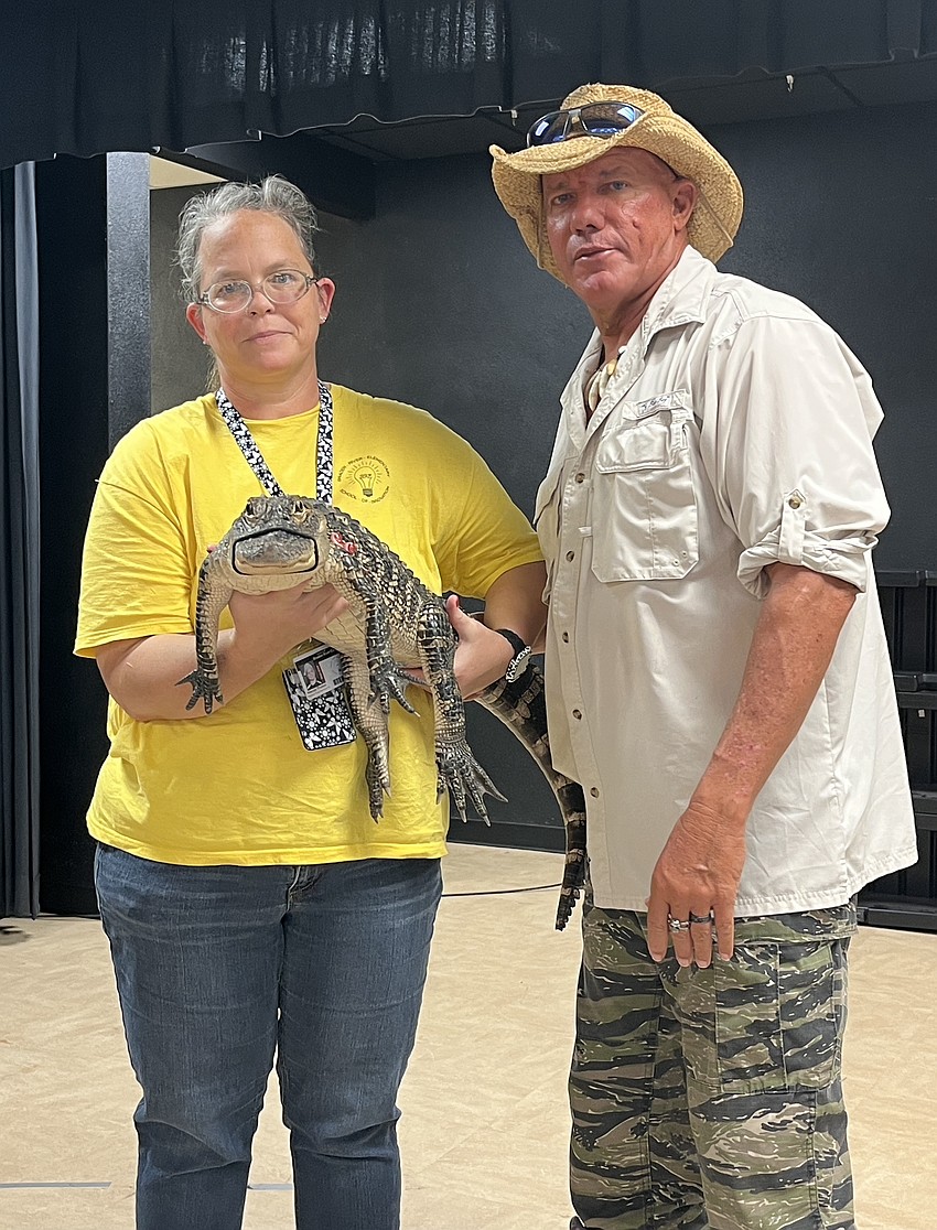Wendy Thielen, a food service worker, holds an alligator with the help of John Kenyon, an educational outreach programmer for Big Cat Habitat.