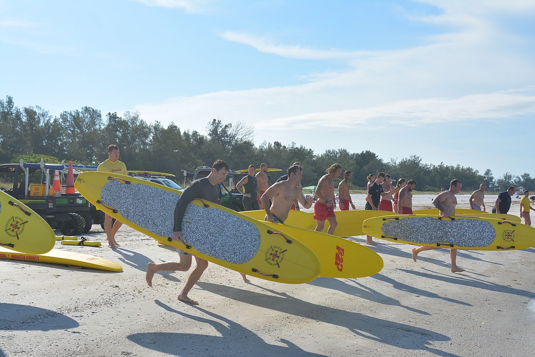 Lt. Daniel Heath (left) and other Longboat Key firefighter paramedics practice running into the water with rescue boards.