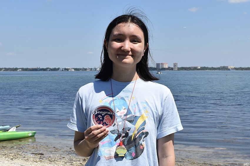 Ringling College student Sandra Lee, a senior in graphic design from Tennessee, holds the magnet she designed to be offered at the event. As part of the Lazarus Engaged Learning Assistantship program, Lee reached out to the Sarasota Bay Estuary Program, whose staff were eager to use her design skills. 