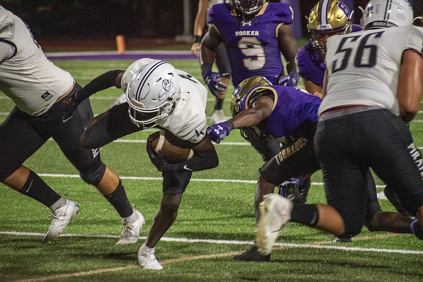 Braden River High junior Marcus Galloway breaks a tackle and stumbles forward against Booker High.