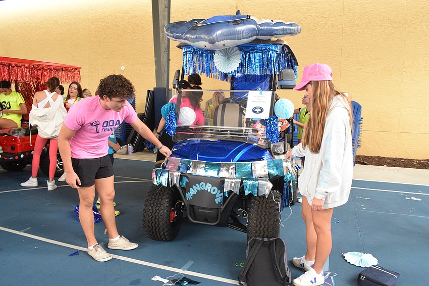 Senior Ryan Mohrmann and junior Kristina Spilka add fringe to the front of their golf cart.