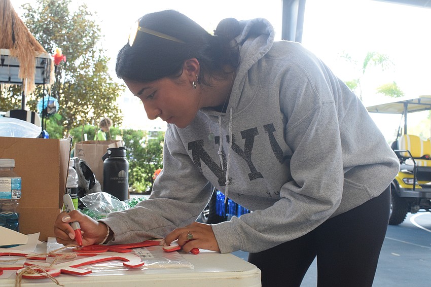 Freshman Amaya Cadena colors an anchor to add to the Sabal house golf cart. Out-of-Door Academy's high school students have been divided into four houses, and each house has a golf cart to decorate for the parade.