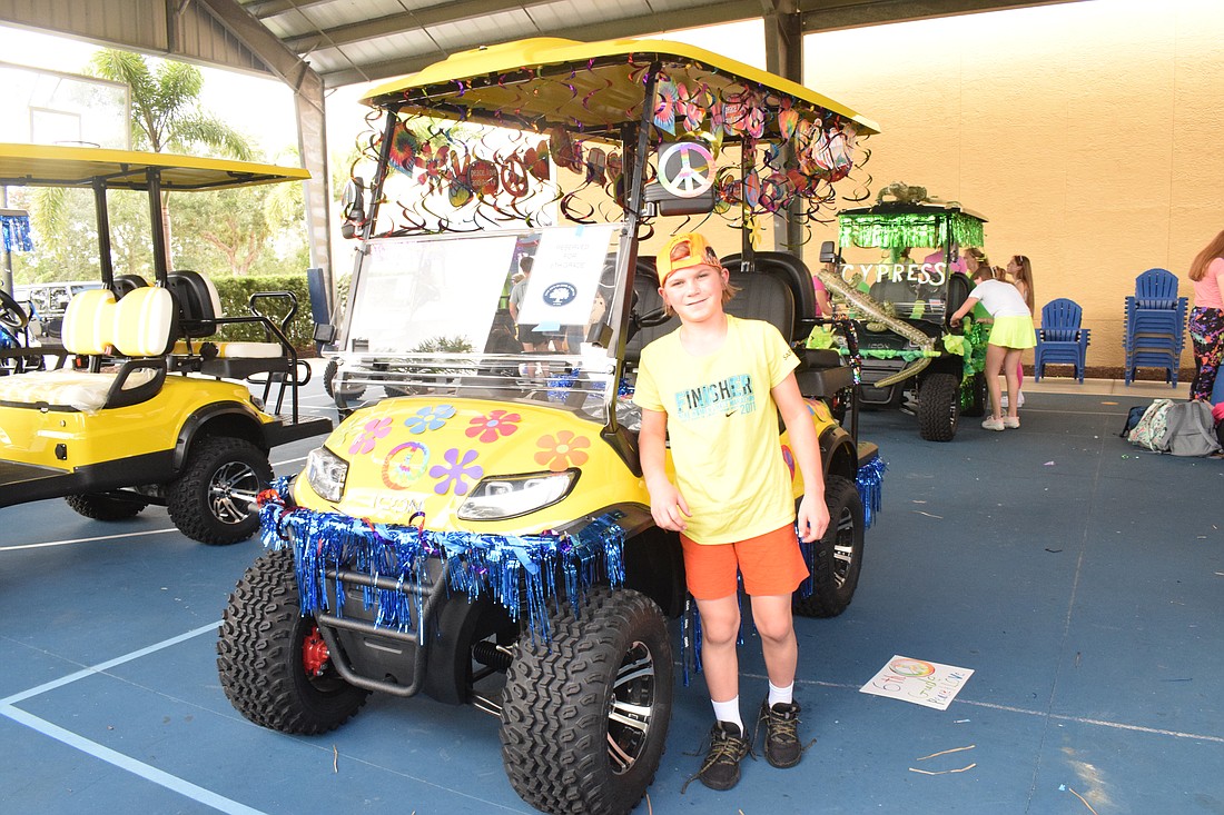 Sixth grader Ethan Burnstein loves how colorful the sixth grade peace themed golf cart is for the homecoming parade.