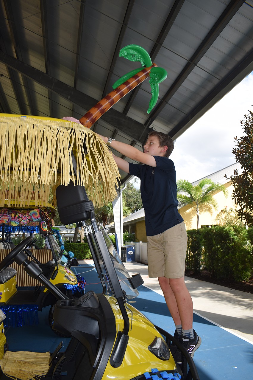 Fifth grader Gabriel Arsenault looks for the perfect place to put an inflatable palm tree on the lower school's history of Out-of-Door Academy's Siesta Key campus themed golf cart.