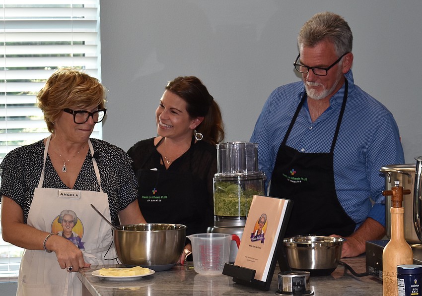 Angela Massaro-Fain and Jess Kruse watch as Bill Smock blends the pesto sauce.