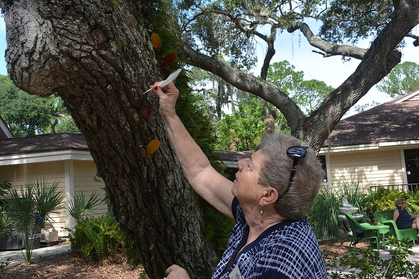 Carol Borsello places a feather in the memory tree at Unity of Sarasota.