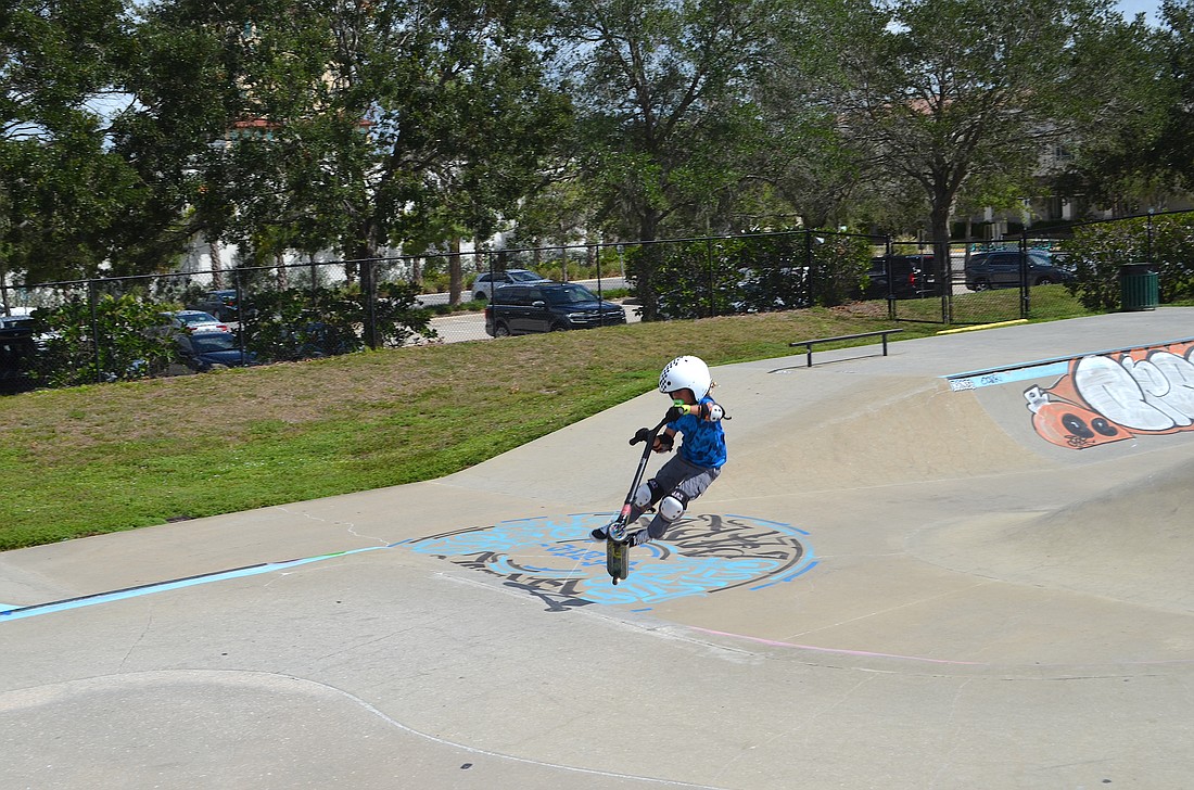 A young rider catches air on a scooter at Payne Skatepark.