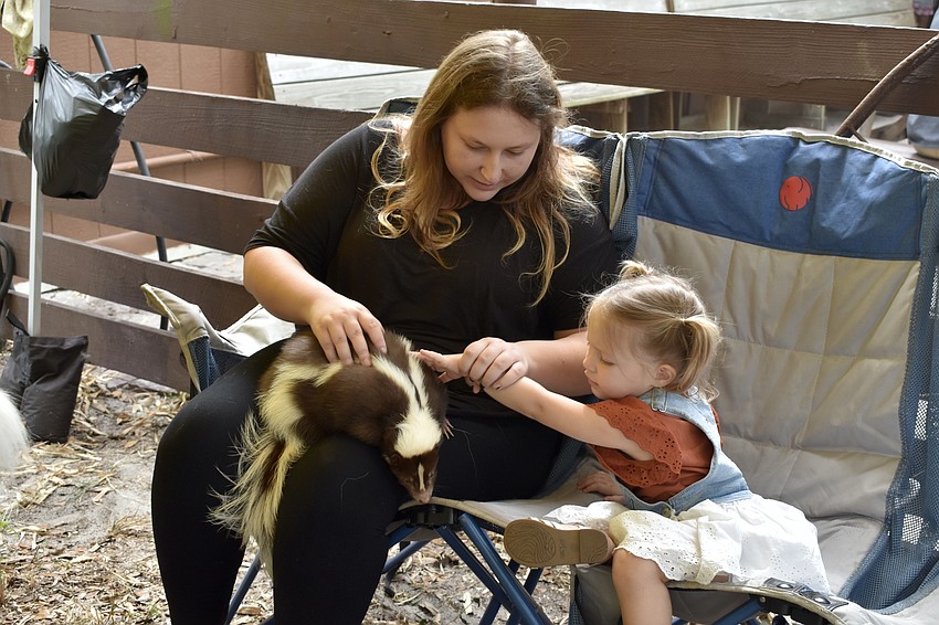 Starla Wilson and Sage Wilson, 2, pet a skunk.