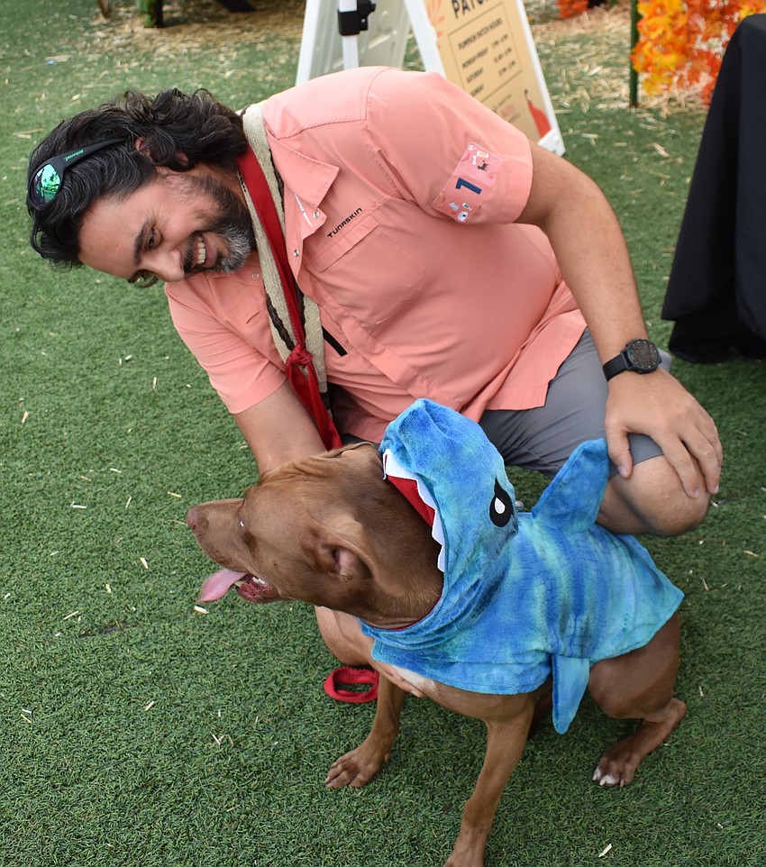 Gus Arevalo of Wimauma makes sure Vizla's shark costume is a good fit before the costume contest at The Green at UTC.