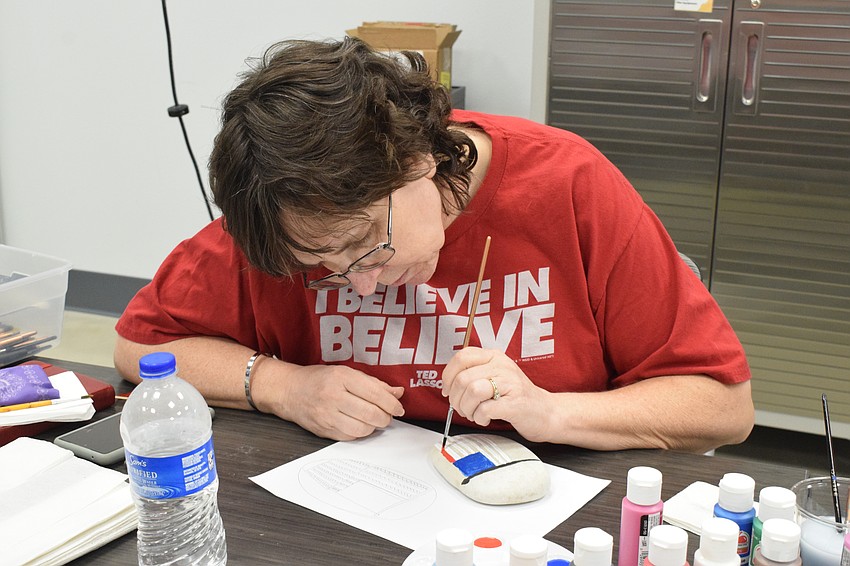 Bradenton's Laura Clay paints a flag on a rock. 