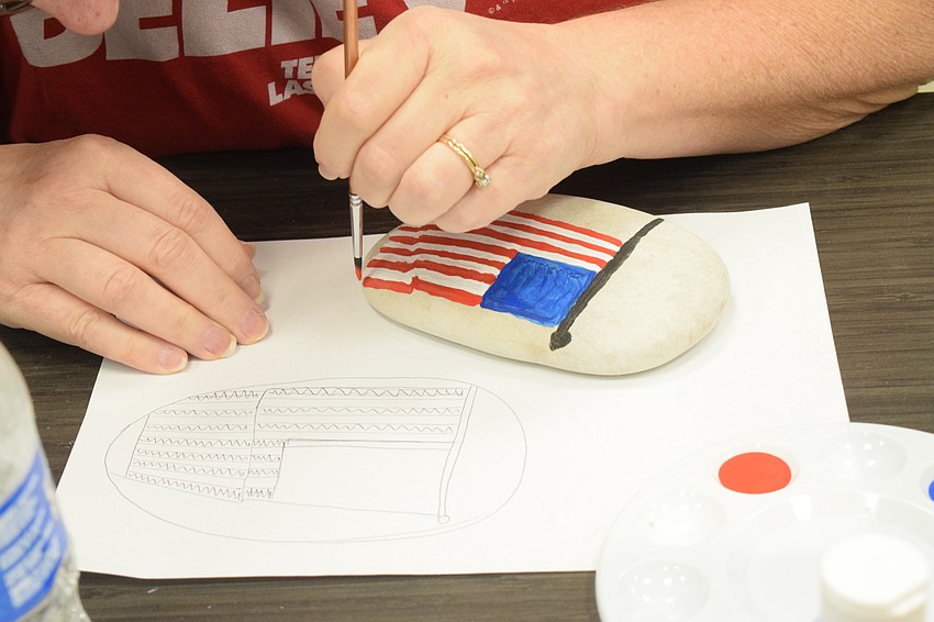 Bradenton's Laura Clay follows her sketch as she paints a flag on her rock.