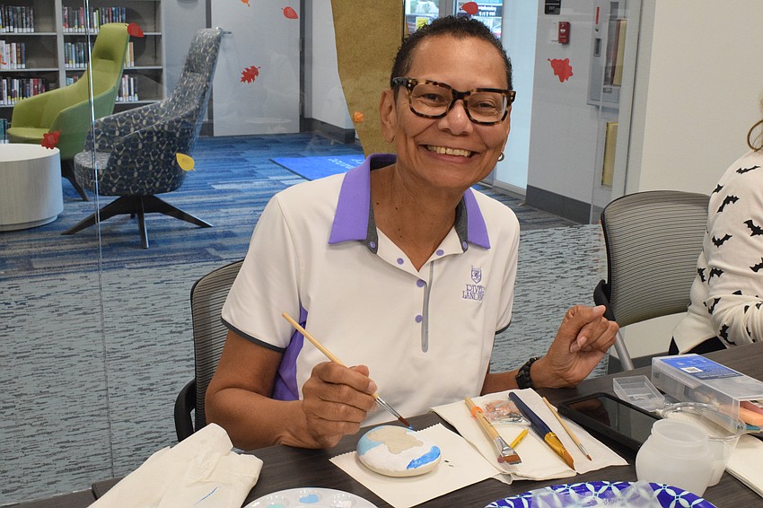 East County's Sonya Bacon paints the sky and water before she paints a frog on her rock. 