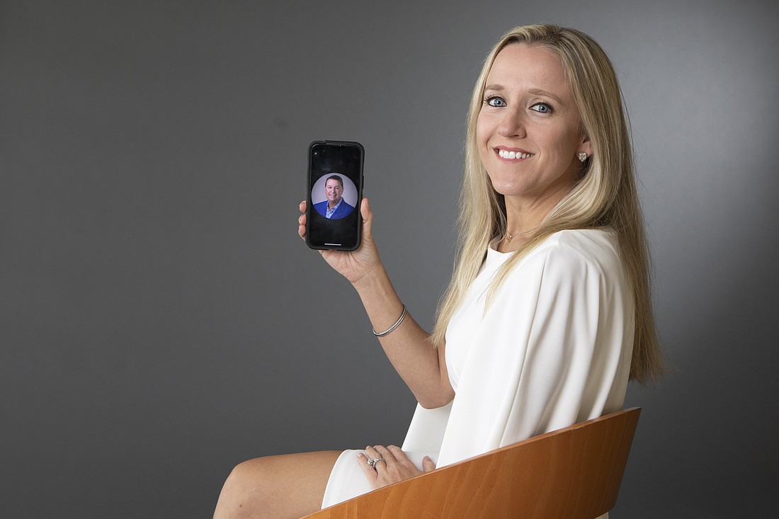 Brie Tulp holding a photo of her mentor, Ian Black Real Estate partner Nick DeVito II