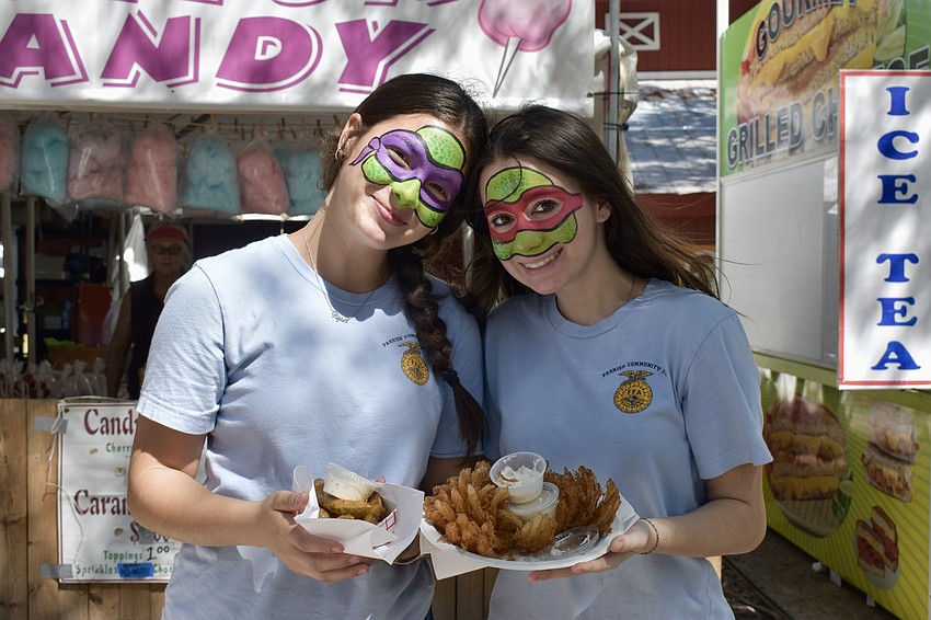Parrish residents Alicia Greenhaw and Eva Gilmore enjoy some fried pickles and onions after working a volunteer shift for the Future Farmers of America.