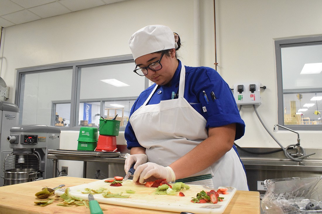 Justice Thornton, a Manatee Technical College baking and pastry arts student, slices kiwis and strawberries.