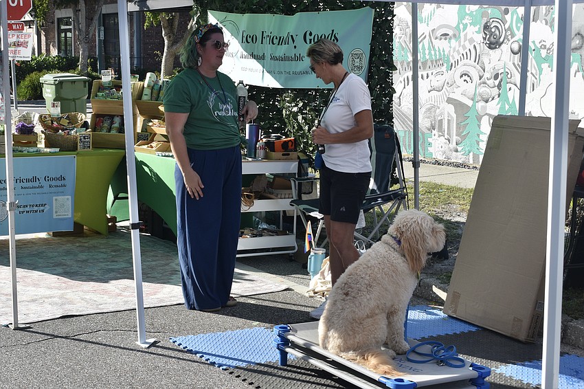 Adjacent vendors Tifanie Page of Eco Friendly Goods and Denise Yenchochic of Dog Training Elite of Southwest Florida socialize with one another, as Tanner sits beside Yenchochic.