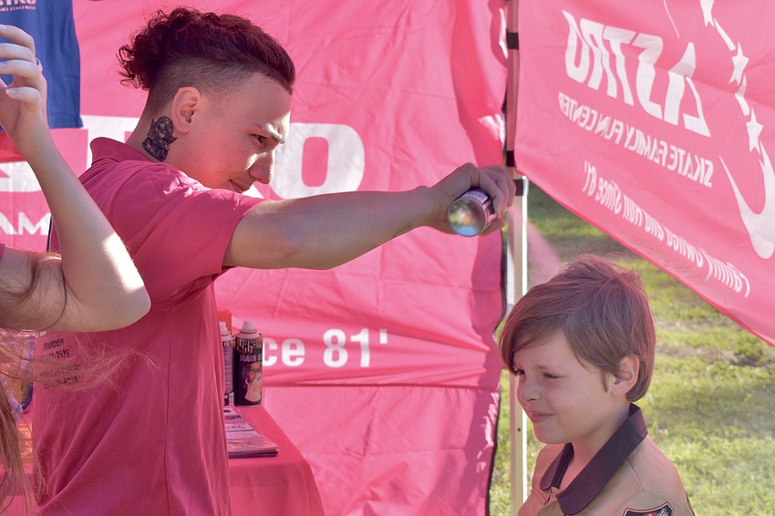 Junior Fernandez of Astro Skate Family Fun Center gives Preston Turner, 10, a chance to try green hair.
