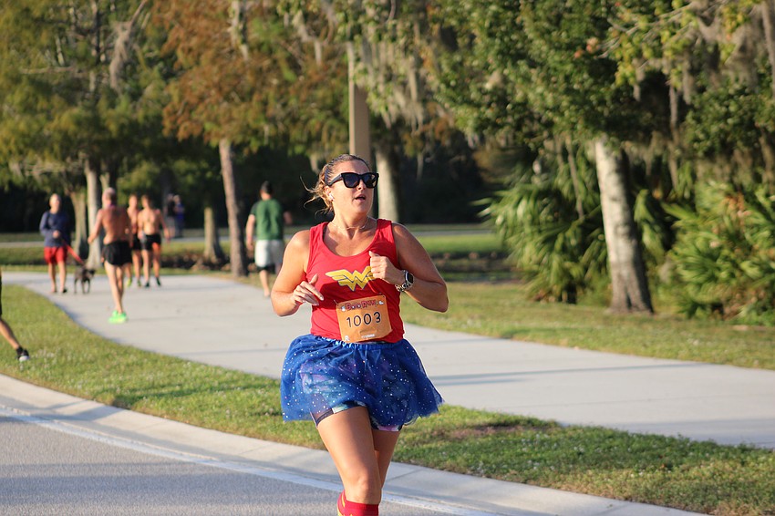 Fit to Run Ambassador Inga Shalmiyeva, who is a health coach for Discover Health in Bradenton, crosses the finish line of the Boo Run.