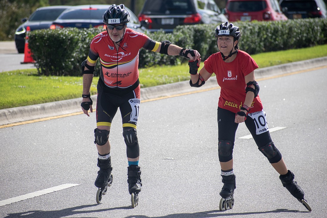 Jose Mateo and Eva Martin hold hands as they prepare to cross the finish line of the Florida Inline Skating Marathon.
