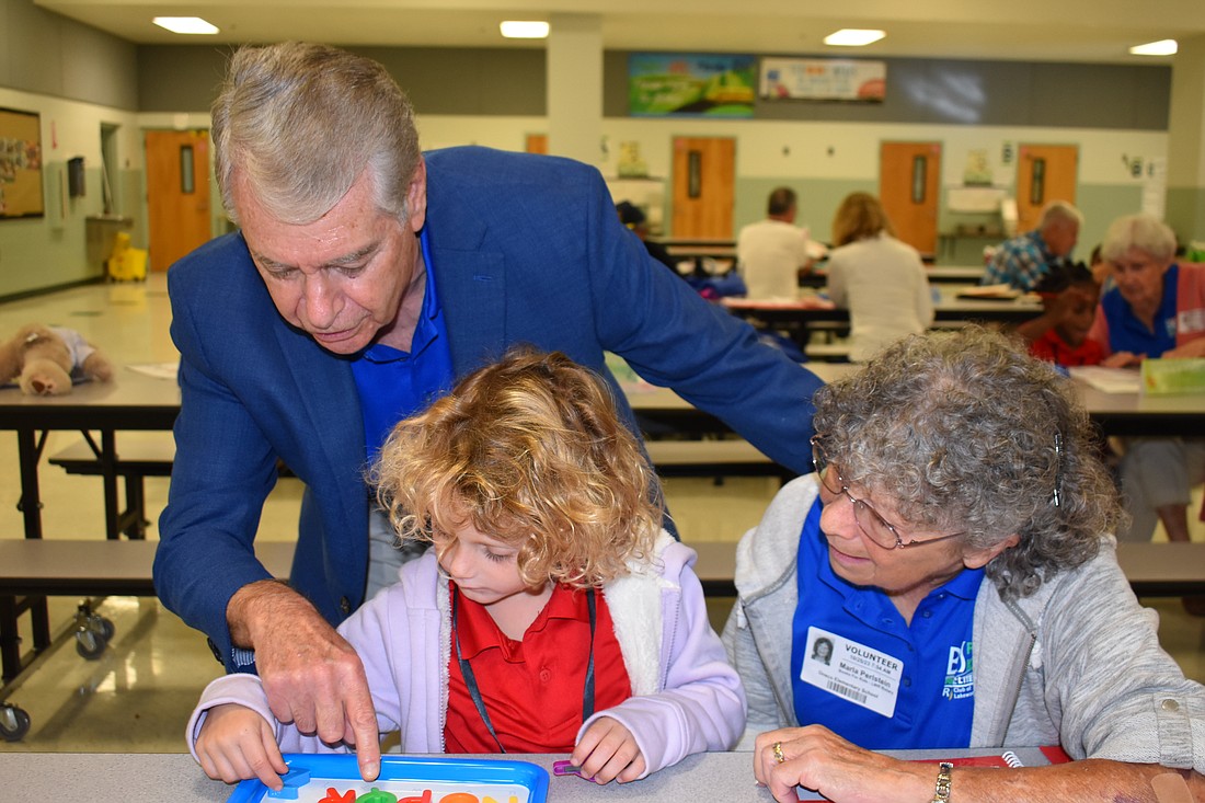 Ted Lindenberg of Books for Kids works with Oneco kindergarten student Cosette Smart and volunteer Marla Perlstein during a 30-minute mentoring session in the school's cafeteria.